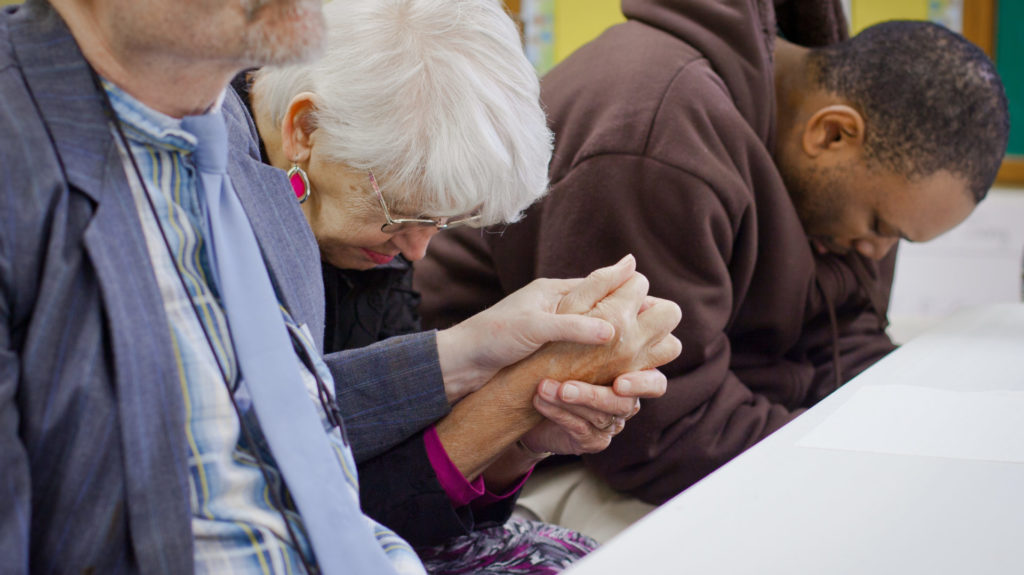 people with hands clasped in prayer